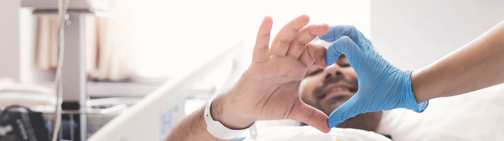 Ein Herzpatient liegt in einem krankenhausbett und formt mit seiner Hand und der Hand eines Arztes ein Herz.  Bildquelle: isayildiz/iStock